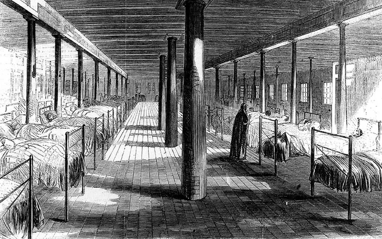 A long vaulted hospital ward with iron bedsteads receding to a vanishing point